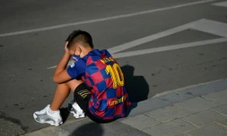 Un garçon avec le maillot de Lionel Messi attend le 30 aoĂ»t 2020 devant le centre d'entraĂźnement du FC Barcelone oĂč les joueurs devaient venir pour un dĂ©pistage du Covid