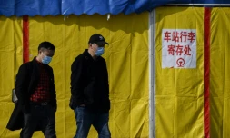 Deux hommes portant des masques de protection contre le coronavirus marchent dans une rue de Jiujiang, le 19 mars 2020 en Chine