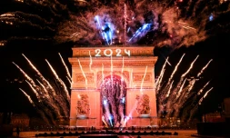 Des feux d'artifice explosent à côté de l'Arc de Triomphe sur lequel "2024" est projeté, sur l'avenue des Champs-Elysées pendant les célébrations du Nouvel An à Paris, le 1er janvier 2024