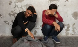 Des Palestiniens pleurent près d'un corps enveloppé dans une couverture à l'hôpital Al-Ahli, le 7 mai 2025, après une frappe israélienne dans la ville de Gaza