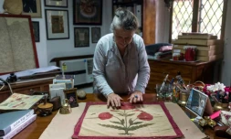 Brigitte Singh étend sur son bureau un carré d'étoffe moghol du XVIIe siècle, orné d'un grand pavot rouge, le 2 juin 2022 à Amber, dans l'Etat du Rajasthan, en Inde