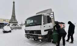 Des hommes changent le pneu d'un camion près d'une réplique de la tour Eiffel à Paris, nom officieux d'un village au Kirghizstan, le 22 janvier 2025