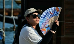 Une touriste utilise un éventail pour se rafraîchir, place Saint-Marc, à Venise, lors d'un épisode de canicule en Europe, le 26 juin 2026