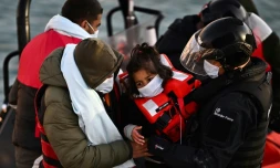 Un membre des garde-côtes britanniques et un autre homme font débarquer une fillette, secourue avec d'autres migrants alors qu'ils tentaient de traverser la Manche depuis la France, à Douvres, dans le sud-est de l'Angleterre, le 18 avril 2022