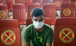 Un passager assis au milieu de sièges sur lesquels sont collés des avertissements à maintenir les distances comme mesure de protection contre le coronavirus, à l'aéroport international Hazrat Shahjalal de Dacca le 25 juin 2020