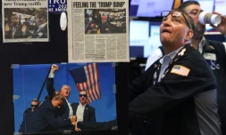 Des coupures de presse et une image du président américain Donald Trump affichées sur un bureau alors que les traders travaillent sur le parquet de la Bourse de New York (NYSE) à la cloche d'ouverture, le 9 avril 2025 à New York