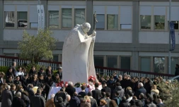 Des personnes prient autour de la statue de Jean-Paul II devant l'hôpital Gemelli à Rome où est hospitalisé le pape François, le 2 mars 2025
