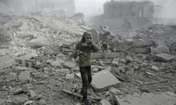 Une fille syrienne apparaît dans les décombres, en tenant sa chaussure, après un raid aérien sur Hamouria, dans la région rebelle de la Ghouta orientale près de Damas, le 9 janvier 2018