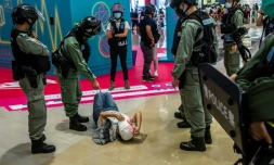 Un policier sermonne une jeune femme qui a été fouillée lors d'une manifestation contre la nouvelle loi imposée par la Chine, à Hong Kong, le 6 juillet 2020