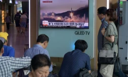 Des personnes passent devant un écran de télévision montrant des images d'archives d'un lancement de missile par la Corée du Nord à Séoul le 26 août 2017