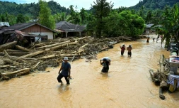 Des habitants progressent dans des eaux de crue au village de Tukka, en Indonésie, le 2 décembre 2025
