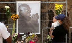 Des personnes déposent des fleurs auprès de l'effigie de Desmond Tutu accrochée devant la cathédrale Saint-Georges au Cap, le 26 décembre 2021