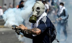 Un opposant vénézuélien porte un masque à gaz lors de heurts avec la police, le 6 avril 2017 à Caracas