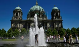 Des personnes se rafraîchissent dans l'eau d'une fontaine, le 2 juillet 2025 à Berlin