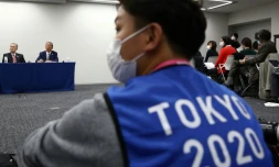 Un photographe portant le gilet des JO de Tokyo 2020lors d'une conférence de presse sur le report de cet événement sportif, à Tokyo le 24 mars 2020