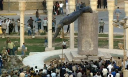 Les Irakiens regardent le déboulonnement à Bagdad de la statue du président Saddam Hussein, aprÚs son renversement consécutif à l'invasion américaine de l'Irak, le 9 avril 2003
