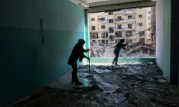 Des membres du personnel d'une ONG libanaise nettoient les débris dans leurs locaux endommagés par une frappe israélienne sur un bâtiment voisin, dans la banlieue sud de Beyrouth, le 2 décembre 2024