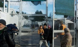 Des migrants avec un bébé sortent du camp migratoire de Moria, deuxiÚme "ville" de l'ßle de Lesbos, le 21 décembre 2017 en GrÚce