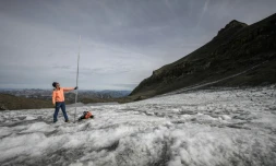 Le glaciologue Matthias Huss brandit une perche de mesure de quatre mètres de long, équivalant à la hauteur de la couche de glace ayant fondu en un an, le 24 septembre 2024 sur le glacier du Scex Rouge, en Suisse