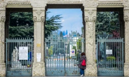 Une femme devant les grilles du cimetière de Bergame (Italie), fermé au public, le 20 mars 2020
