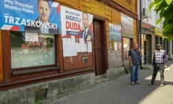 Deux hommes discutent devant des affiches de campagne des candidats du second tour de l'élection présidentielle polonaise le 9 juillet 2020 à Raciaz (Pologne)