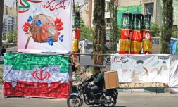 Un automobiliste passe devant une banderole représentant le guide suprême iranien tué, l'ayatollah Ali Khamenei, ainsi qu'un drapeau iranien, à Téhéran le 29 avril 2026