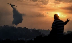 Un bombardier d'eau dĂ©verse sa cargaison sur un feu de forĂȘt dans le centre du Portugal, devant un villageois, Ă Chaveira le 22 juillet 2019