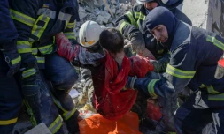 Des sauveteurs évacuent un soldat ukrainien sauvé aprÚs avoir été coincé 30 heures dans les débris d'une caserne militaire touchée par des roquettes russes, à Mykolaïv, dans le sud de l'Ukraine, le 19 mars 2022