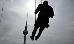 Un homme se balance à 120 mètres au dessus de Berlin sur la plus haute balançoire d'Europe, juchée sur le toit d'un hôtel face à la Fernsehturm, emblème touristique de la ville de l'Alexanderplatz, le 31 juillet 2024