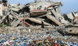 Une Palestinienne marche entre des détritus et un immeuble détruit, dans le camp de réfugiés de Nousseirat, dans le centre de la bande de Gaza, le 29 janvier 2026