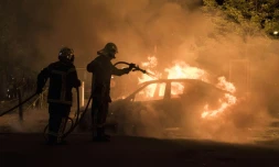 Un pompier lutte contre les flammes d'une voiture incendiée dans le quartier Malakoff de Nantes, le 4 juillet 2018