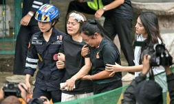 L'épouse (C) d'un professeur tué par un adolescent dans un lycée au nord de Bangkok est emmenée vers une ambulance, dans le district de Bang Kruai, en Thaïlande, le 7 août 2026