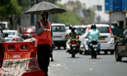 Un employé fait la ciculation protégé par un parapluie par les fortes chaleurs à New Delhi, en Inde, le 29 mai 2024