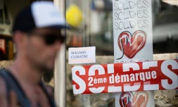 Un homme passe devant une vitrine où une affichette indique que le magasin est climatisé, pendant les soldes, le 13 juillet 2022 à Nantes