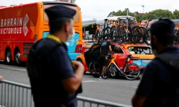 Un policier près du bus et d'une voiture de l'équipe Bahrain le 15 juillet 2021 avant le départ de la 18e étape du Tour de France à Pau