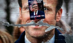 Une affiche électorale pour le candidat de la gauche radicale Jean-Luc Mélenchon apposée sur une autre affiche pour Emmanuel Macron, le 19 avril 2022 à Paris