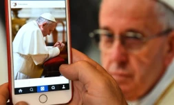 Un homme regarde le compte Instagram du pape sur son écran de portable, le 19 mars 2016 à Rome
