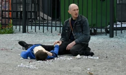 Un proche à genoux devant le corps d'un adolescent tué par une frappe de missile russe à un arrêt de bus à Saltivka, près de Kharkiv a northern district of the second largest Ukrainian city of Kharkiv le 20 juillet 2022