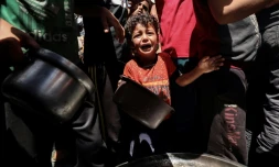 Un enfant pleure au milieu de Palestiniens qui attendent de recevoir un repas chaud distribué par une association caritative locale à Nousseirat, dans le centre de la bande de Gaza, le 24 mai 2025