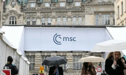 Des gens s'abritent de la pluie en passant devant un accès à la Conférence de Munich sur la sécurité (MSC), le 12 février 2026 à Munich