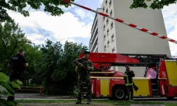 Un membre de l'opération Sentinelle monte la garde aux côtés d'un policier et d'un pompier sur le site d'un incendie qui s'est déclaré dans un immeuble résidentiel à Décines-Charpieu, en périphérie de Lyon, le 11 mai 2026