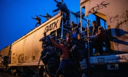 Des migrants illégaux agrippés à un train de marchandises en direction des Etats-Unis, traversent de nuit le village de Las Patronas, le 9 août 2018 dans l'Etat du Veracruz, au Mexique