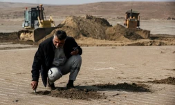 Un ingénieur irakien examine le sol tandis que des bulldozers dégagent des dunes de sable et extraient de l’argile dans le désert au sud de Samawah, le 21 décembre 2025