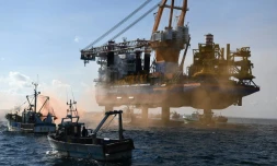 Des bateaux de pĂȘche entourent un bĂątiment, l'Aeolus, chargĂ© de poser les fondations d'un chantier Ă©olien, pour protester contre cette construction, le 7mai 2021 dans la baie de Saint-Brieuc