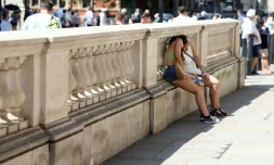 Des personnes se protégent du soleil derrière un mur, le 24 juin 2026 à Londres