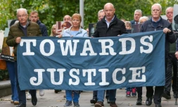 Des proches des victimes du "Bloody Sunday" brandissent une banderole sur laquelle est écrit "Towards Justice" (En faveur de la justice) alors qu'ils se rendent à pied au tribunal de Belfast, en Irlande du Nord, le 16 octobre 2025