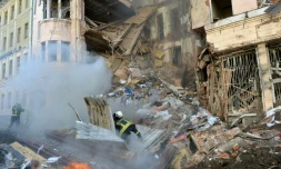 Des pompiers s'affairent auprÚs d'un immeuble éventré par une frappe russe à Kharkiv, dans l'est de l'Ukraine, le 14 mars 2022