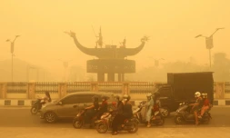 Des motocyclistes portant un masque de protection circulent dans une Ă©paisse brume causĂ©e par des feux de forĂȘt et de terres dans la rĂ©gion de Palangkaraya, dans le Kalimantan central, le 24 octobre 2026 en IndonĂ©sie