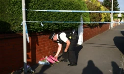 Un policier dépose des fleurs, le 29 juillet 2024, en hommage aux victimes d'une attaque au couteau qui a fait deux morts et neuf blessés parmi des enfants participant à un atelier de danse à Southport, au nord-ouest de l'Angleterre.