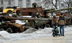 Un couple et un enfant à vélo se promènent dans l'exposition en plein air d'équipements militaires russes détruits à Kiev, le 15 février 2026